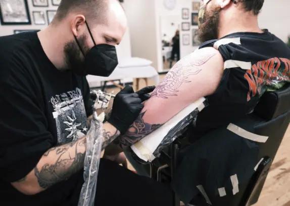 a person getting a tattoo on another person's arm