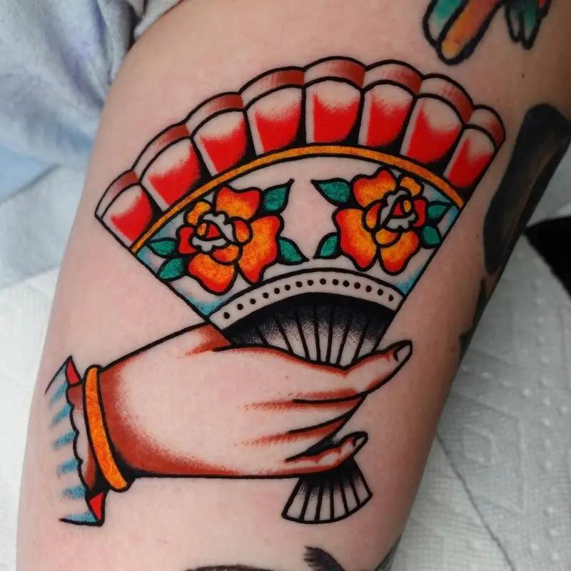 a hand tattoo holding a folding fan