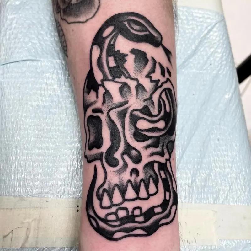 a skull and snake tattoo at the forearm